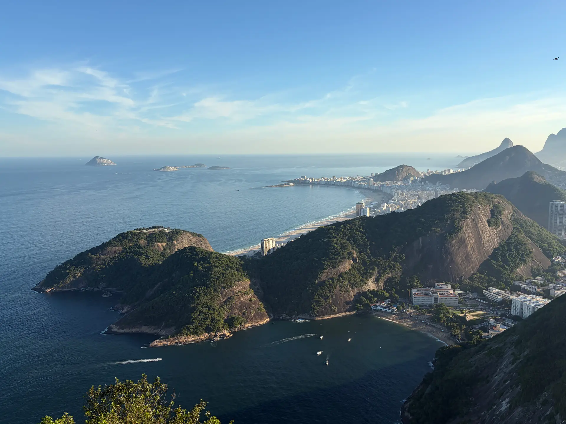 Une vue panoramique sur le littoral de Rio de Janeiro, avec ses collines verdoyantes, ses plages de sable et ses bâtiments en bord de mer, sous un ciel bleu limpide : un décor idéal pour trouver l'inspiration sur ce qu'il y a à faire à Rio de Janeiro en 3 jours.